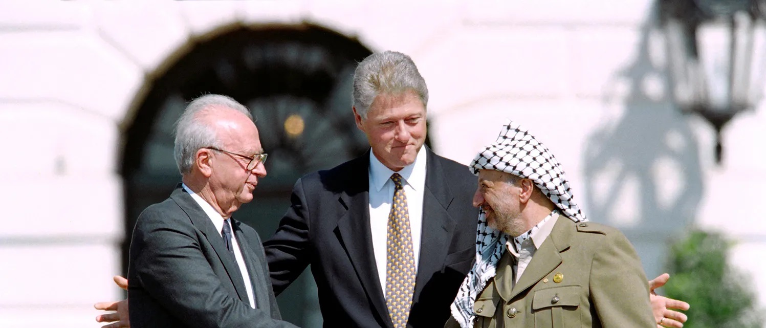 Yitzhak Rabin, Bill Clinton og Yasir Arafat gir hverandre et håndtrykk under signering av Oslo-avtalen.