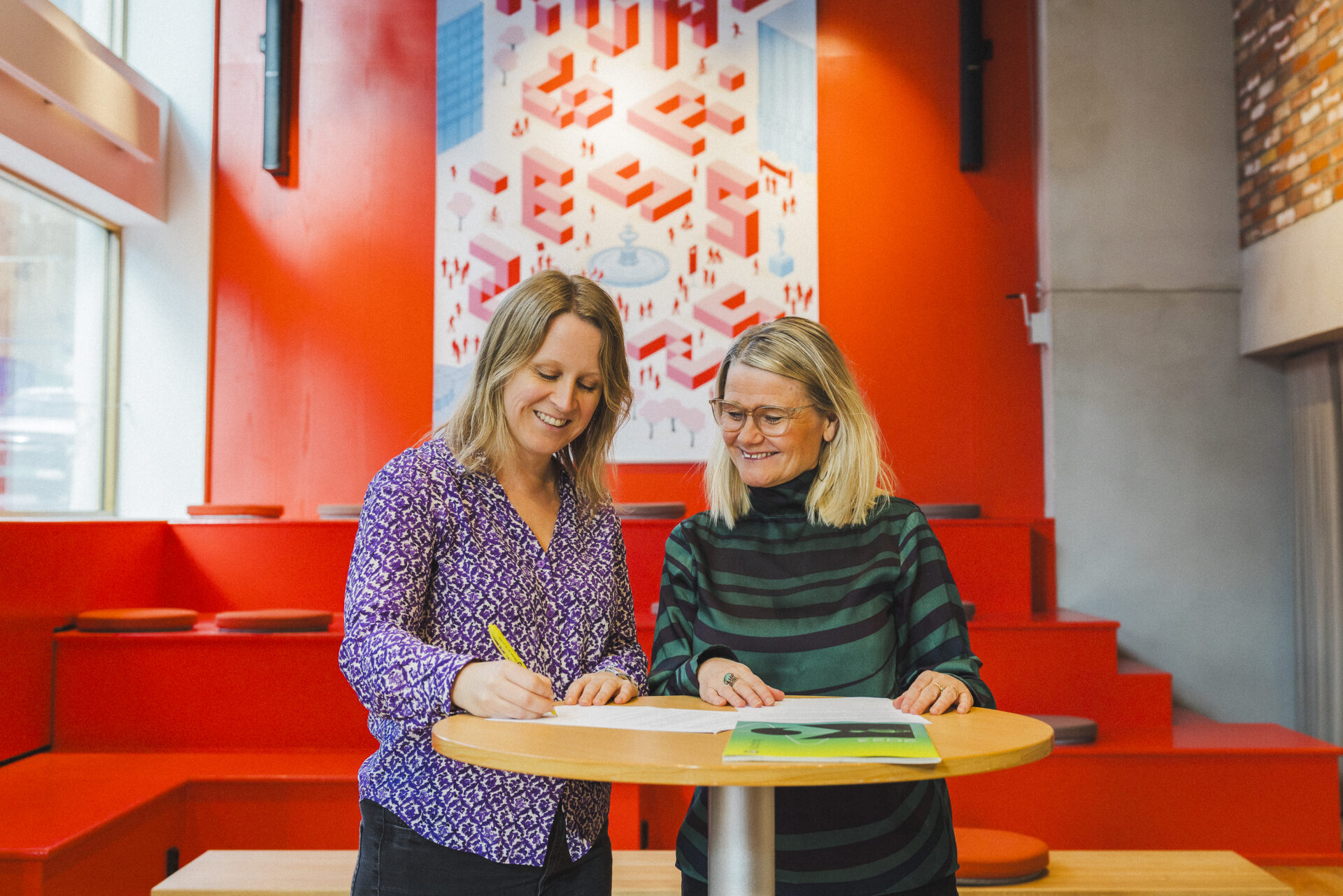 To kvinner signerer avtale. Foto.