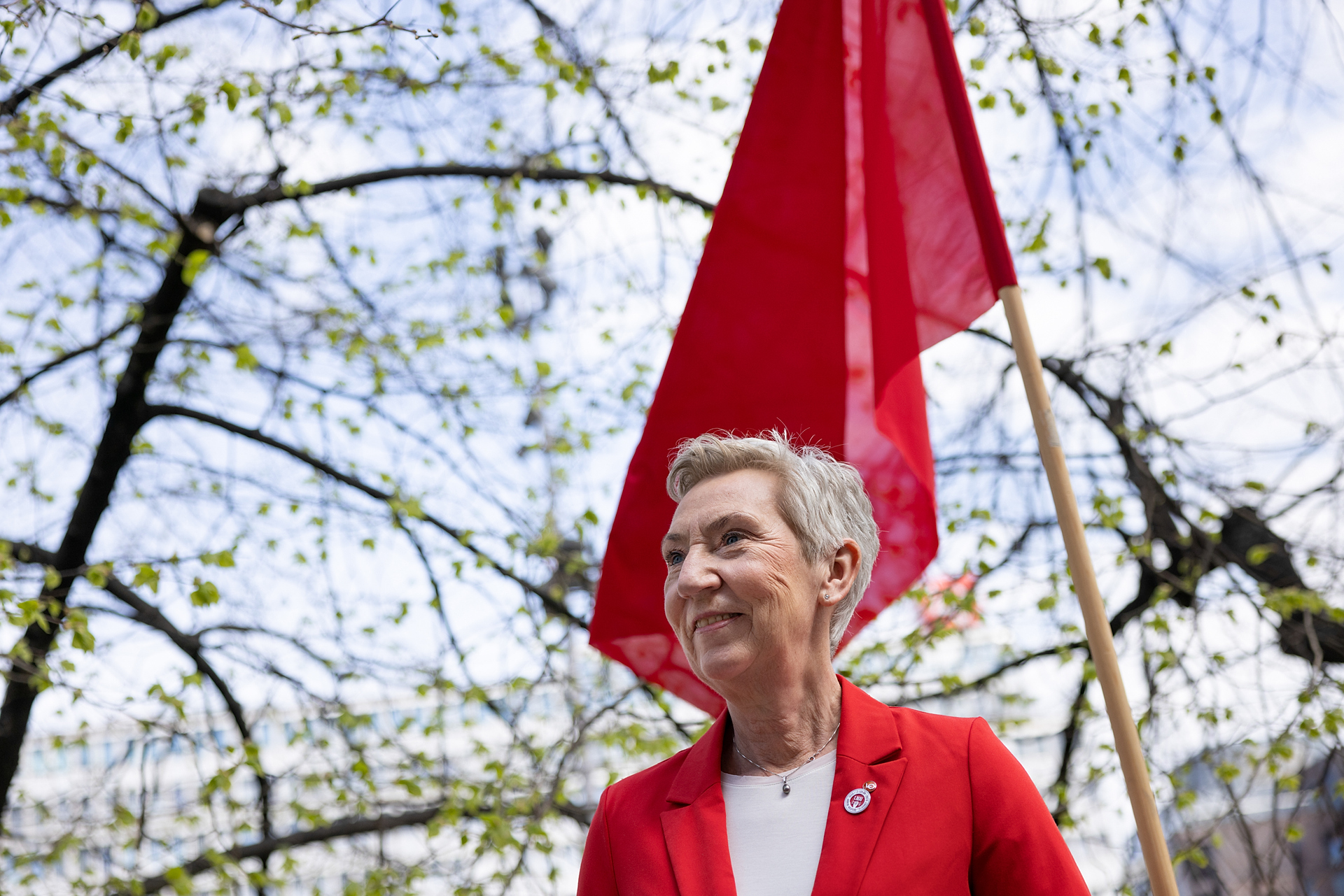 LO-leder Peggy Hessen Følsvik ute, foran et rødt flagg. Foto. 