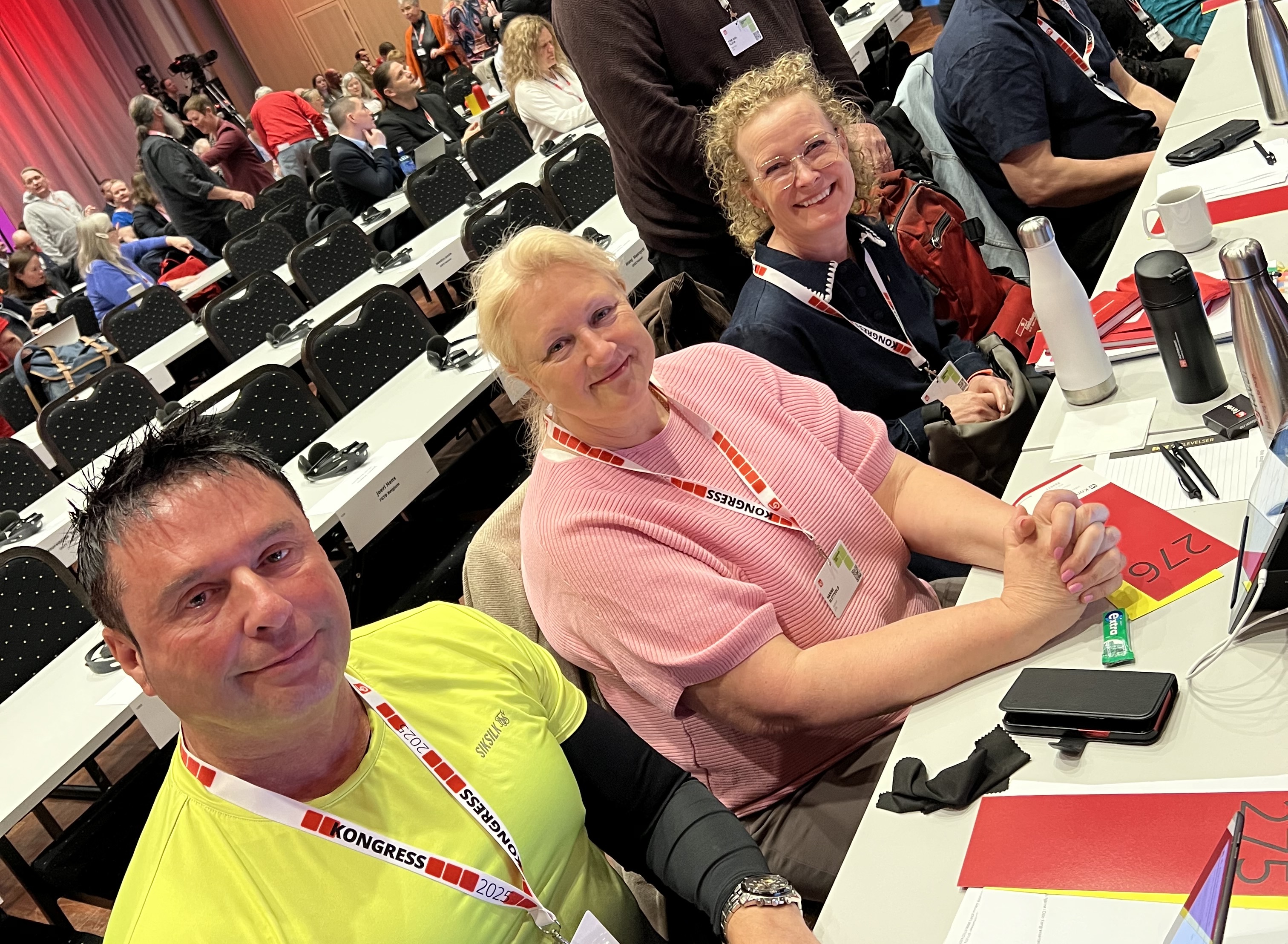 tre blide mennesker sitter i salen på LO-kongressen 2025