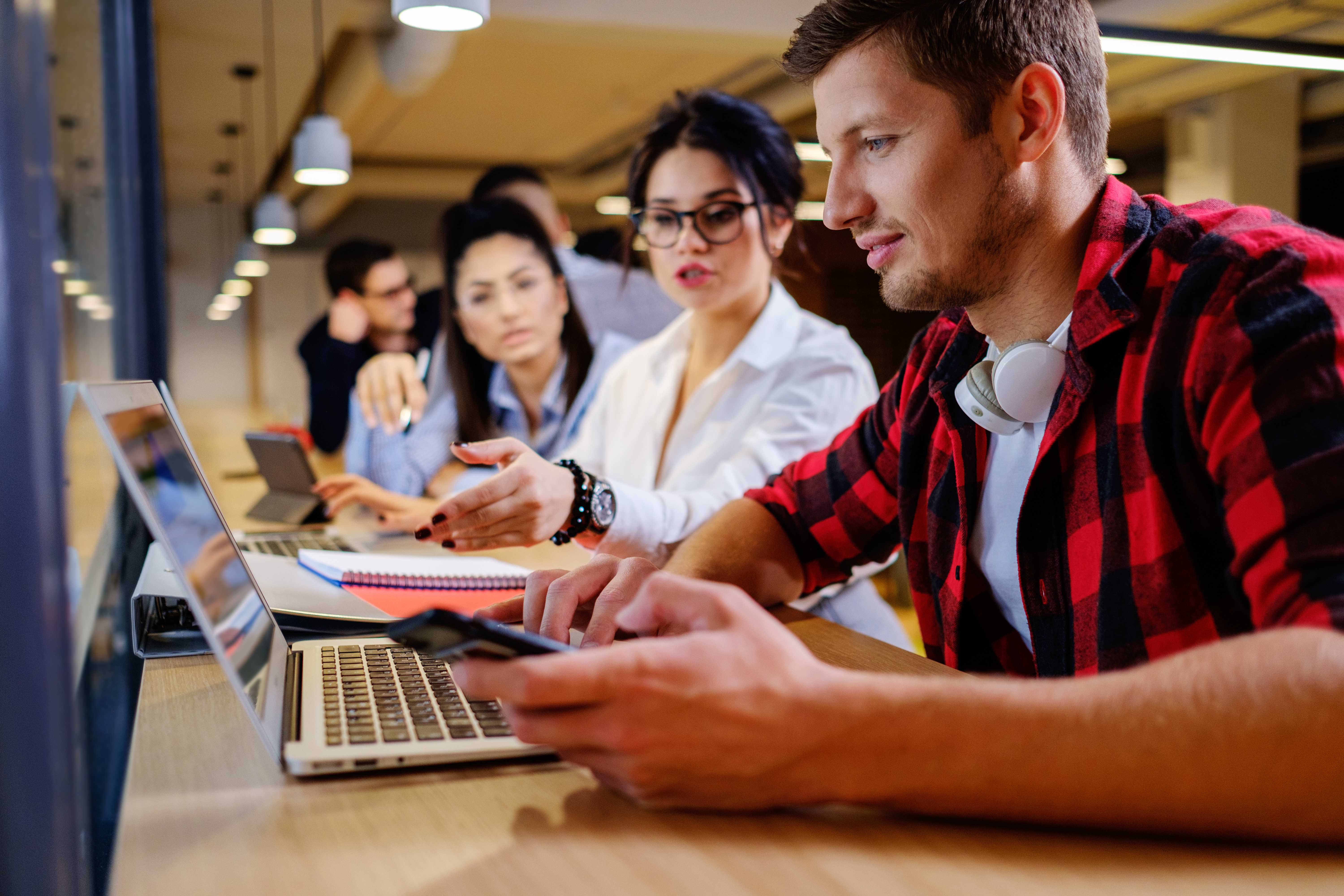 Flere sitter i fellesskap rundt en pc. Illustrerer kontorfellesskap.