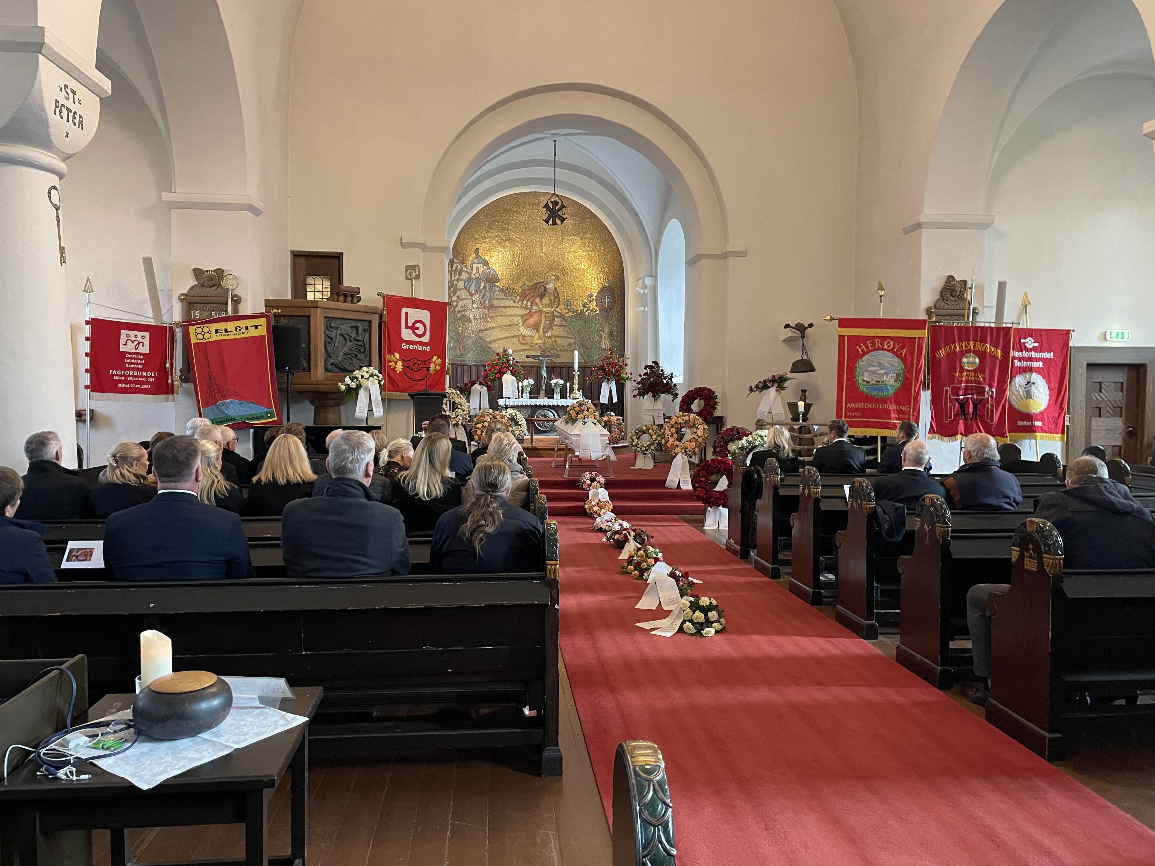 et kirkerom med kiste og faner