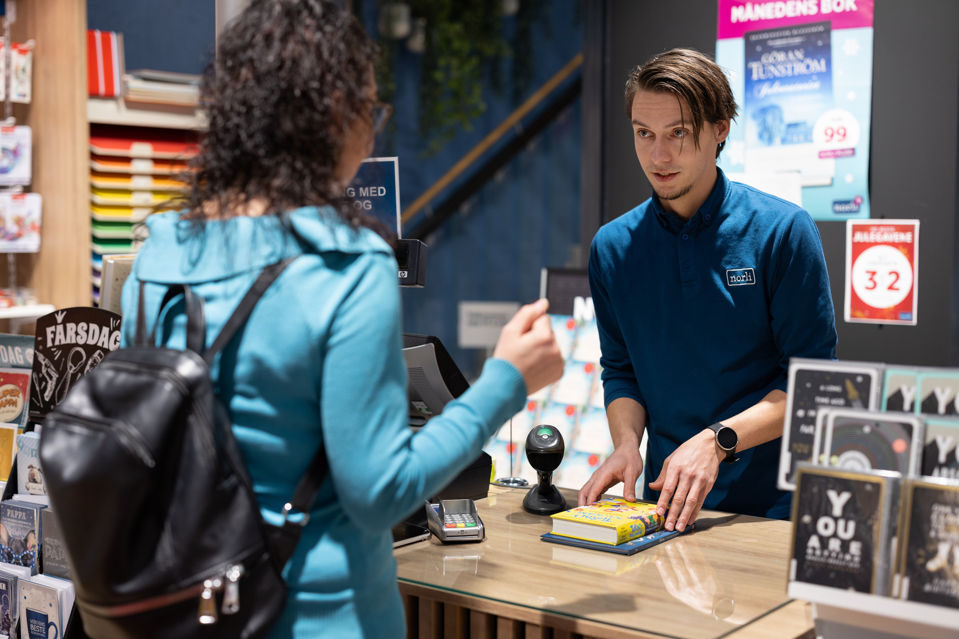 En ung mann ekspiderer en kvinne i en bokbutikk. Foto.