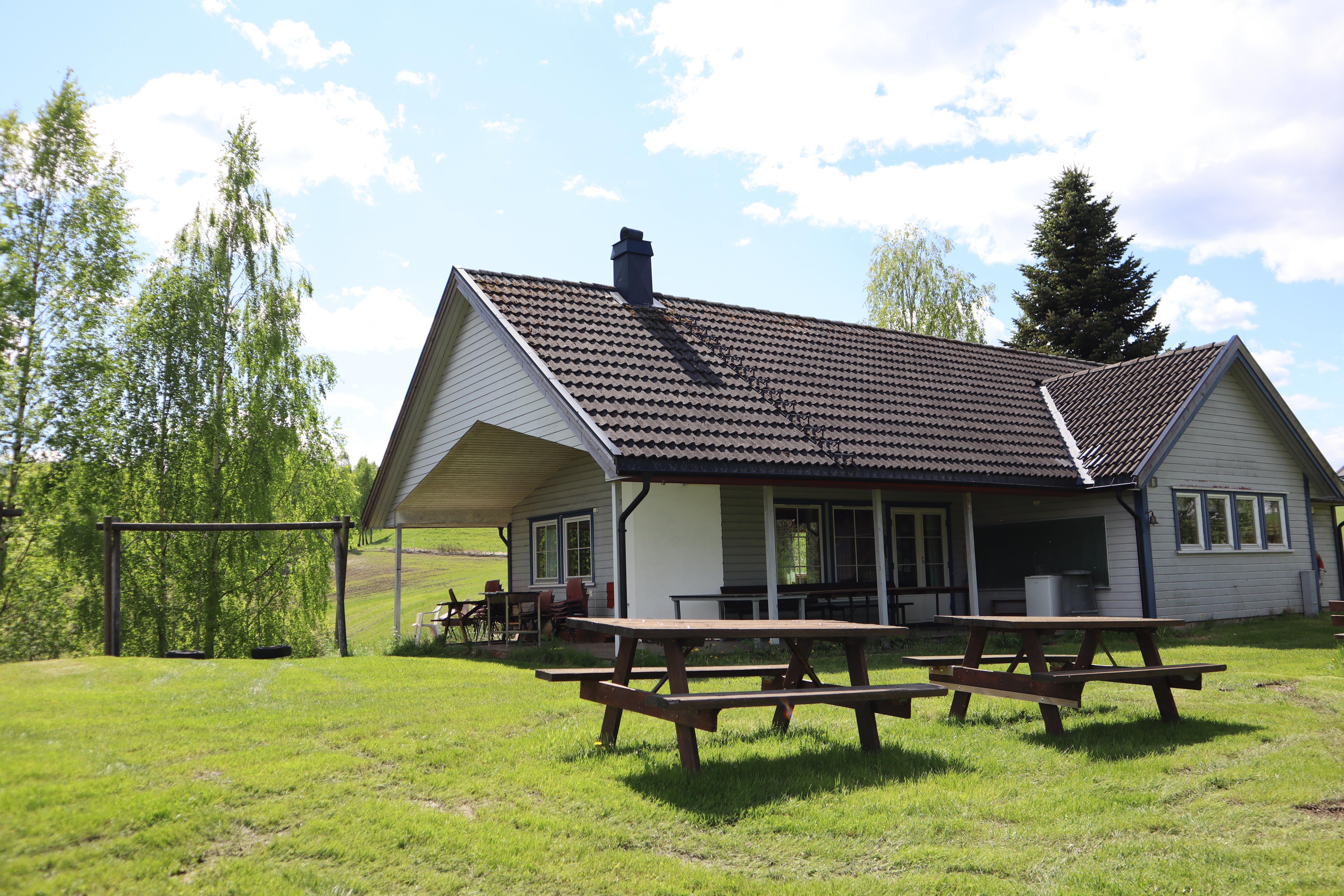 Bildet viser hovedhuset på Hanes feriekoloni fra en grønn plen.
