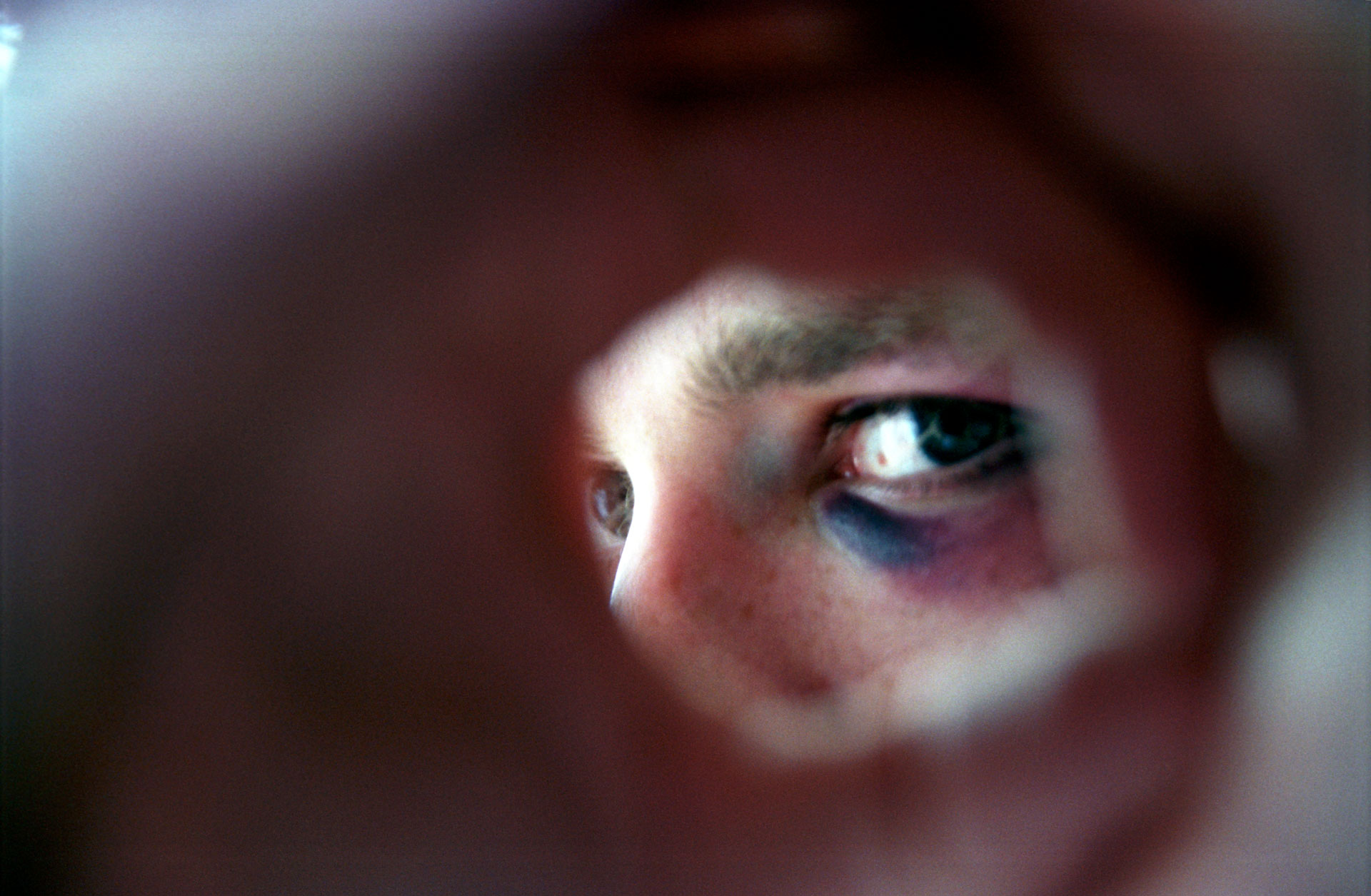 en hånd hvor tommel og pekefinger lager en ring og gjennom der ser vi del av et ansikt