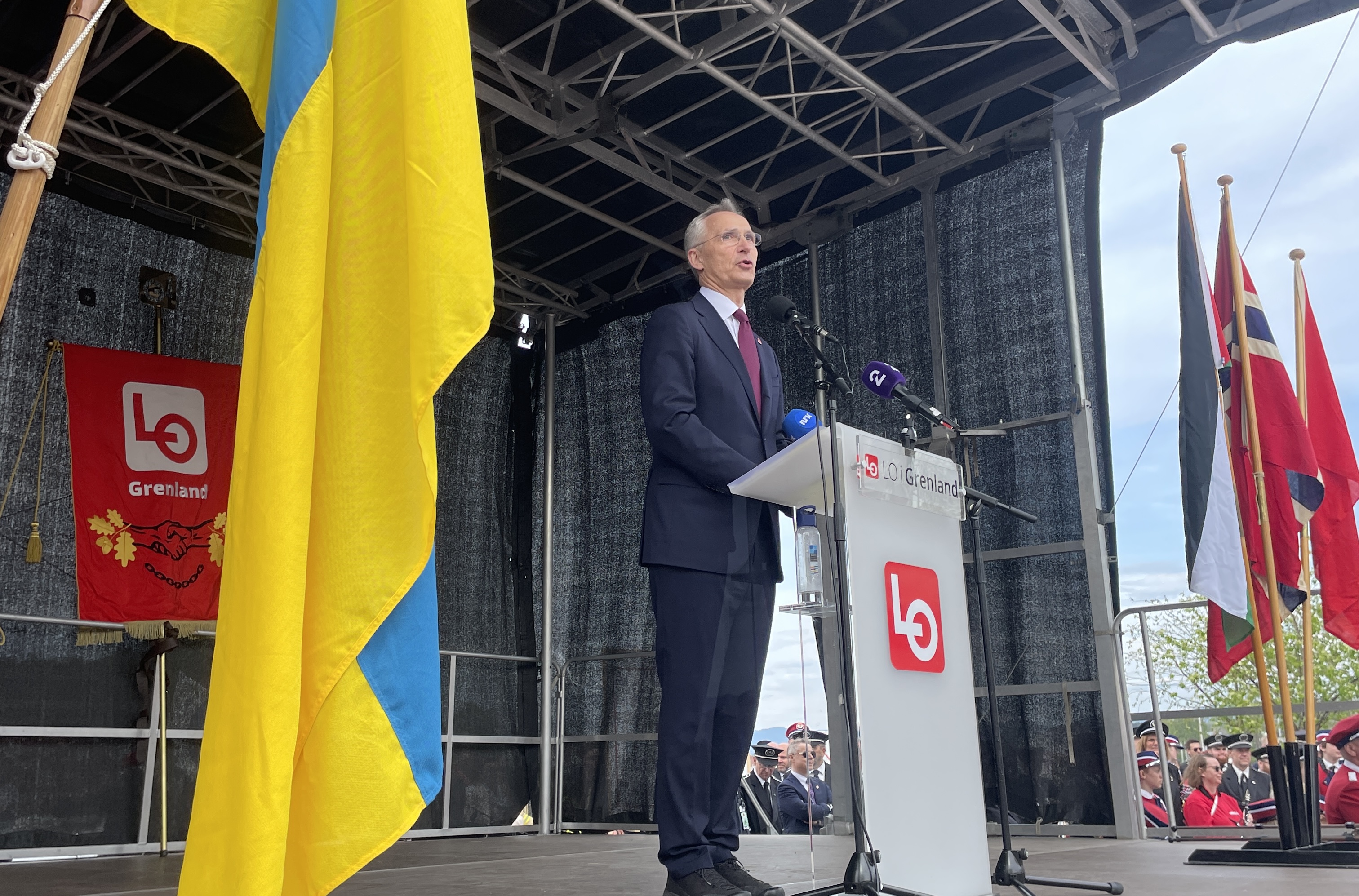Finansminister Jens Stoltenberg fra Arbeiderpartiet står bak talerstolen til LO i Grenland da han holder 1. mai-tale i Porsgrunn. I forgrunn det Ukrainske flagget og bak fanen til LO i Grenland.