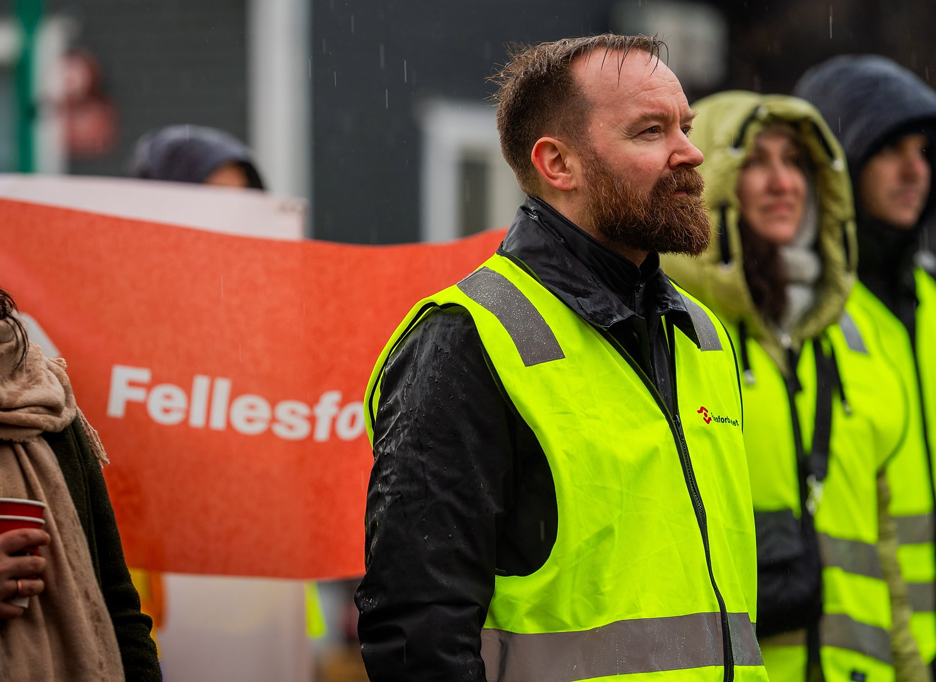 Streikevakt med gul vest som står foran et Fellesforbundet banner. Foto.