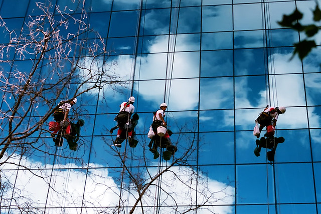 vindusvaskere som henger utenfor et glassbygg