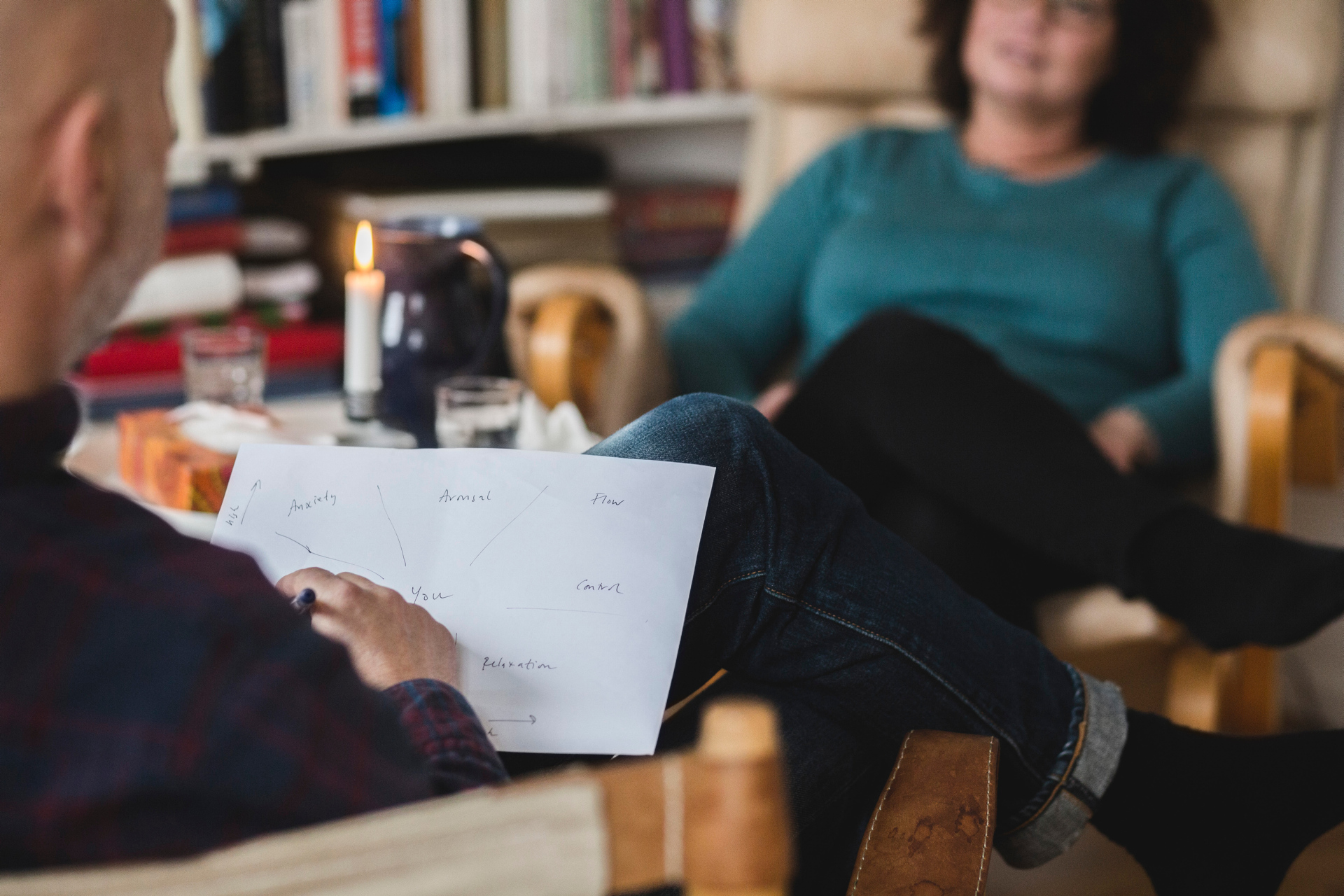 kvinne med grønn topp sitter i en stol og prater med en terapeut på andre siden av bordet