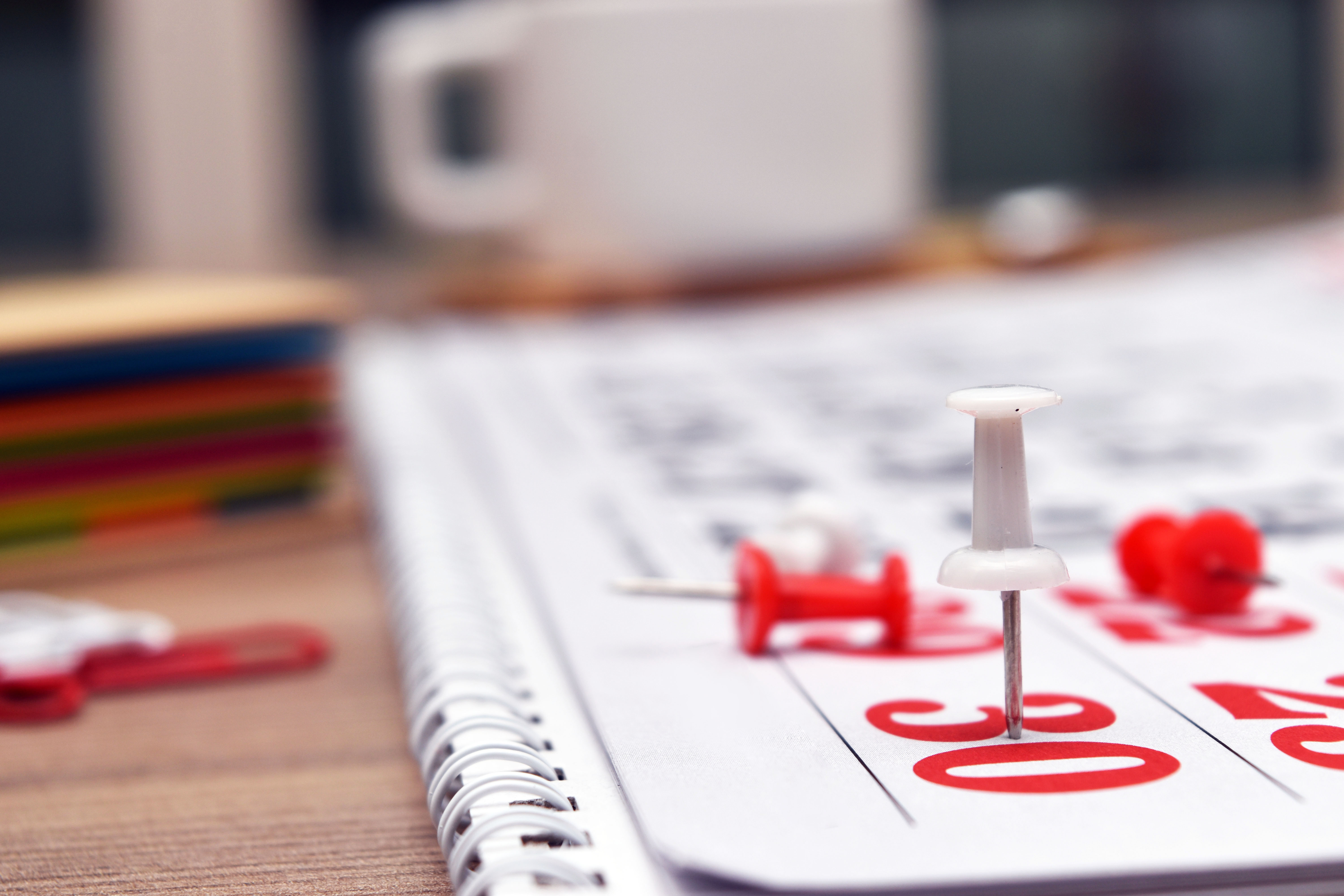 en kalenderblokk med hvite og røde stifter festet til dato