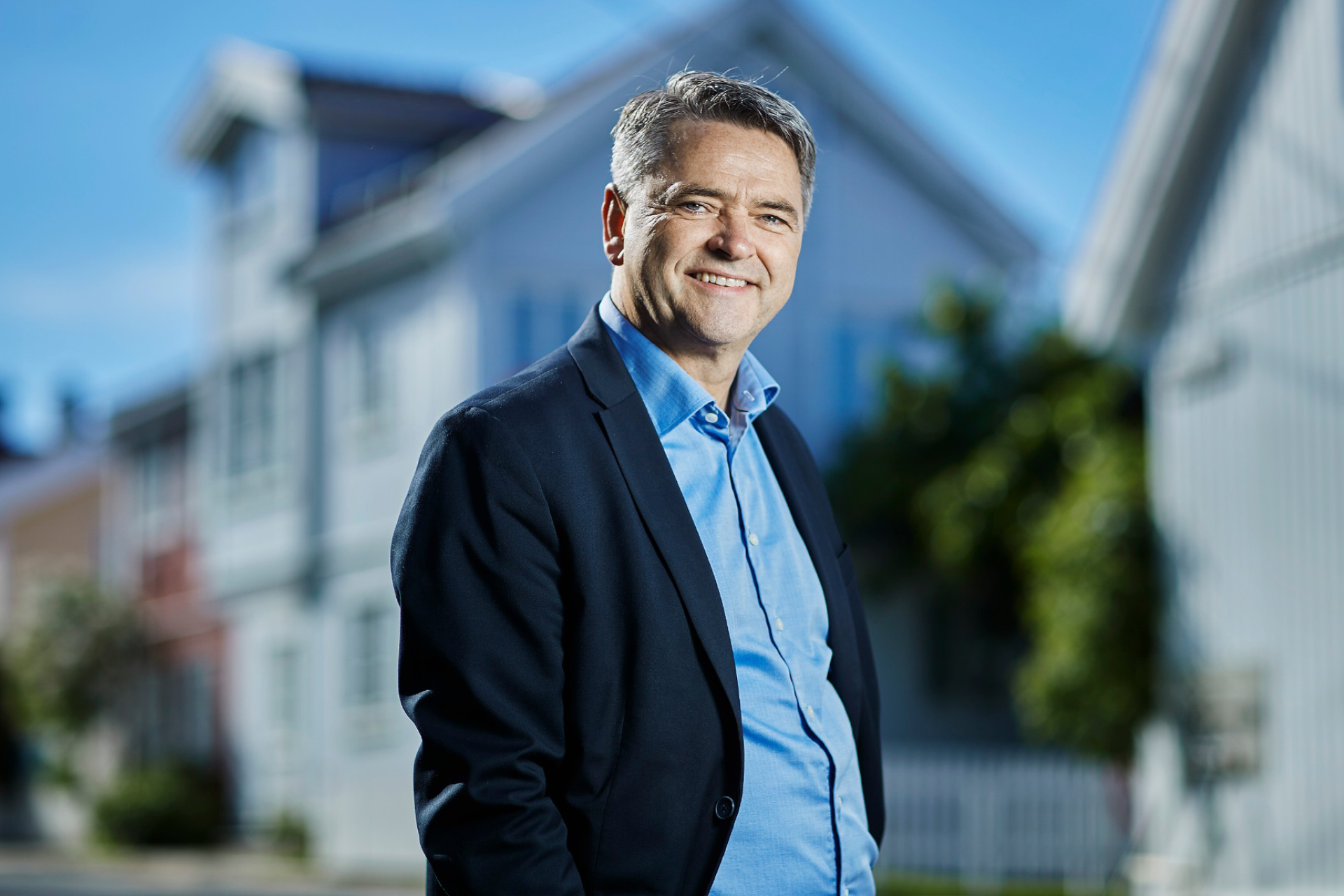 Forbrukerøkonom Magne Gundersen står i forgrunn, bak noen hus som er fadet ut.