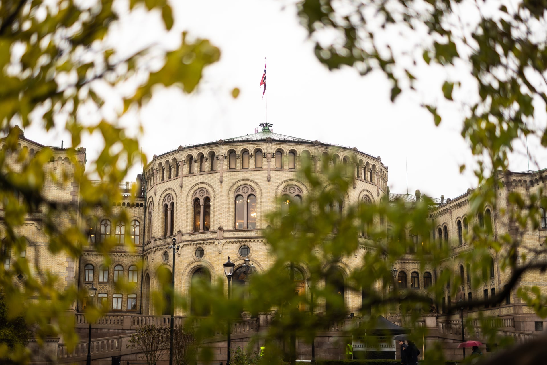 Bilde av Stortinget bak høsttrær. Foto.