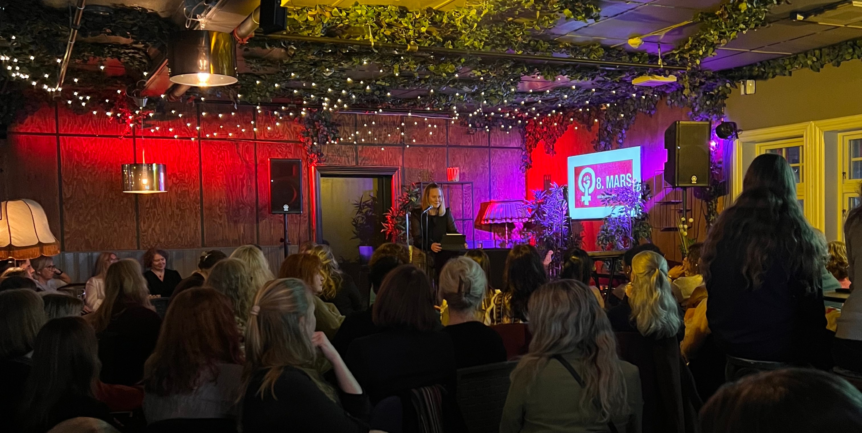 Kvinne som taler foran mange mennesker på 8. mars