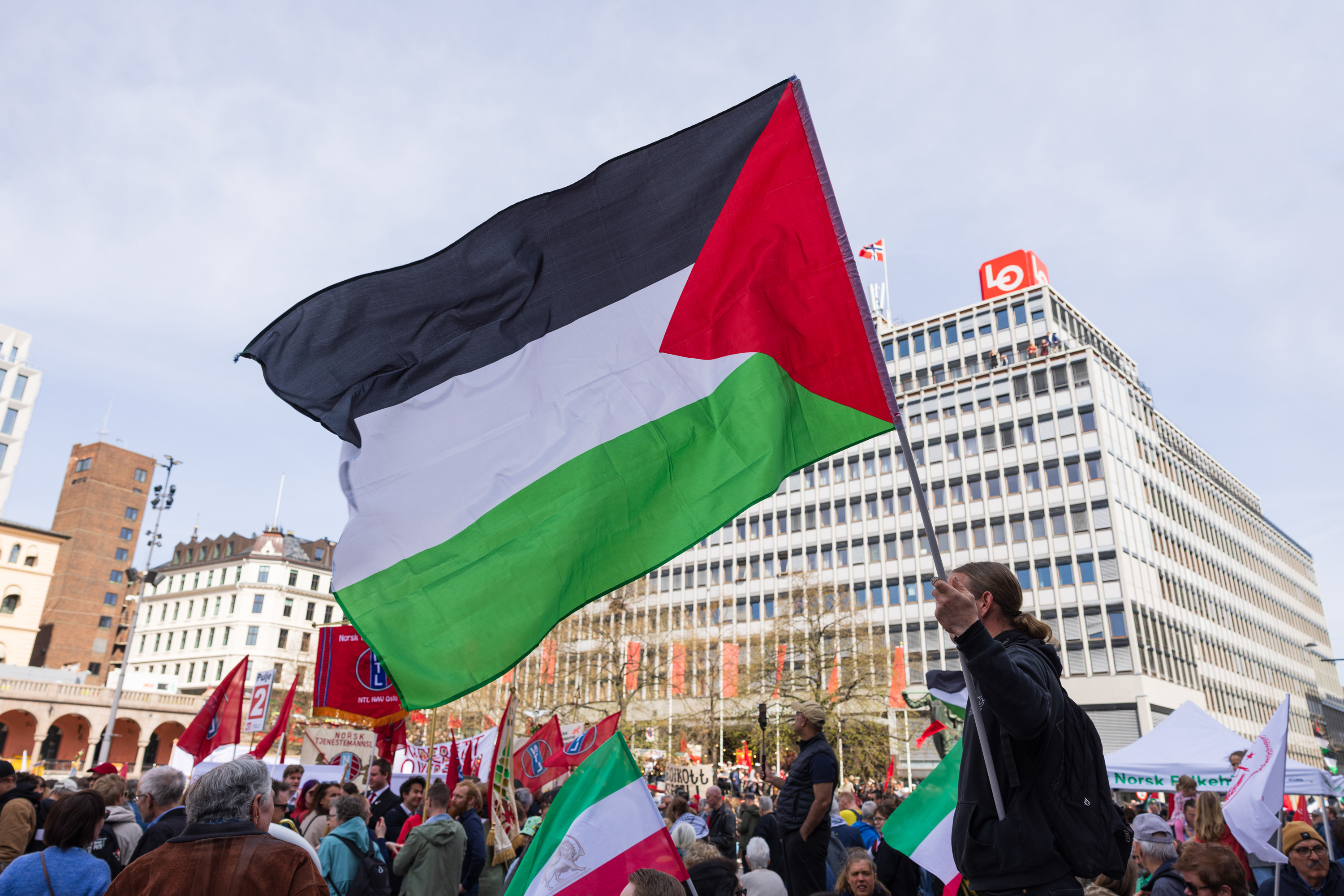 Palestinaflagg i vinden  med folkemengde bak utenfor Folkets hus i Oslo 1. mai 2024