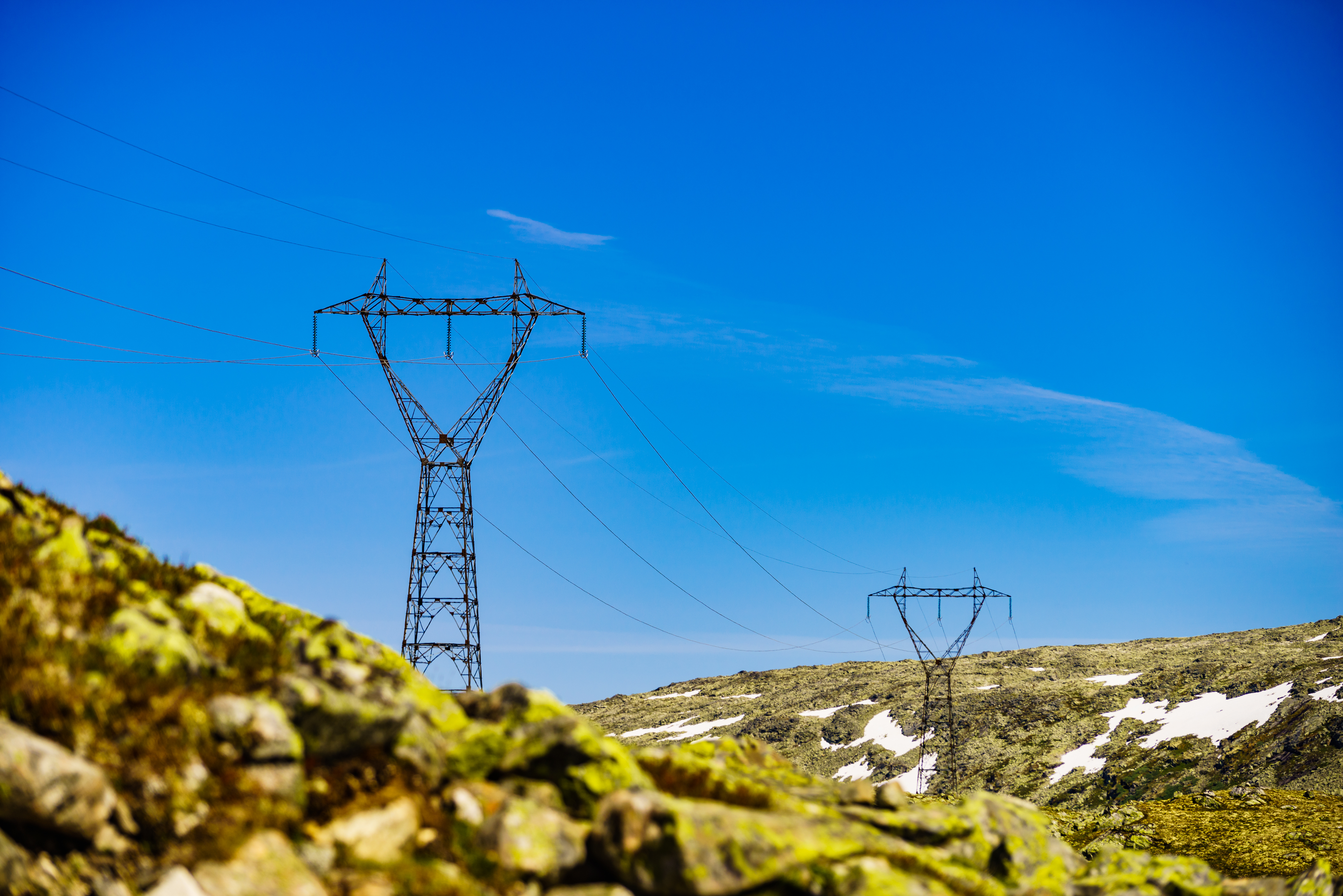 Electricity transmission pylons, power lines high voltage towers in norwegian mountains landscape.