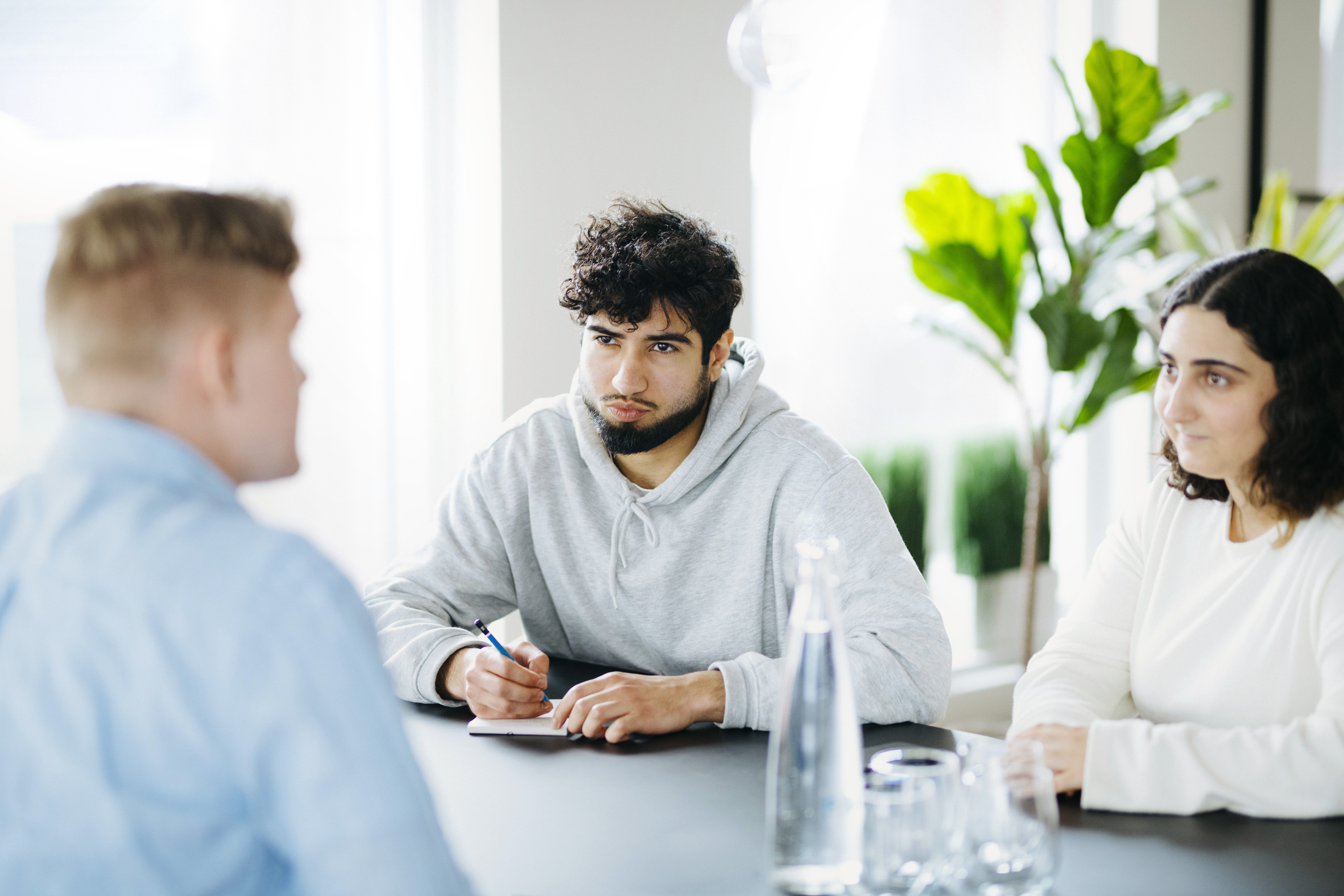 Unge mennesker sitter rundt et bodt. Foto.