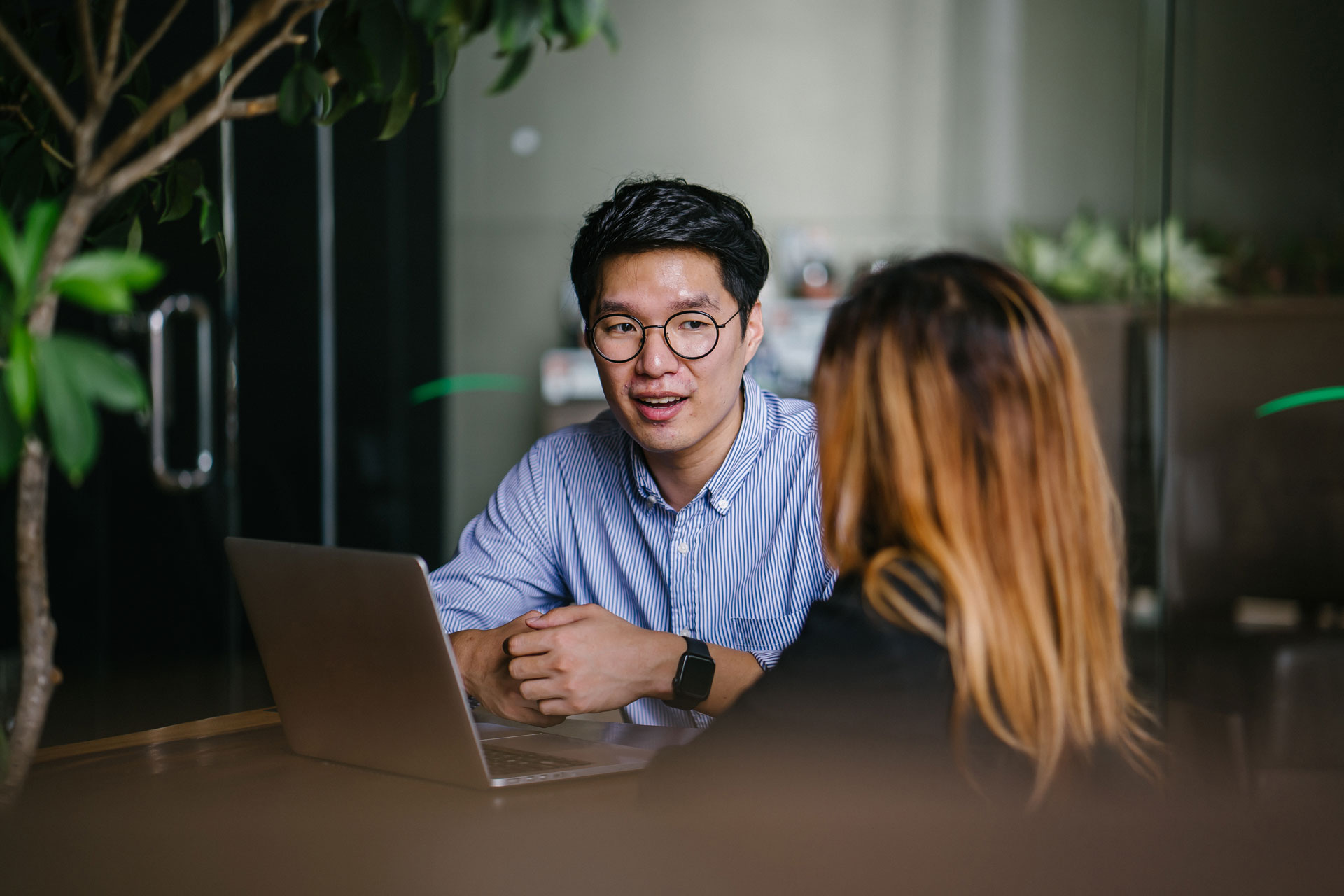 En mann og dame står sammen over en bokhylle og snakker. Foto.