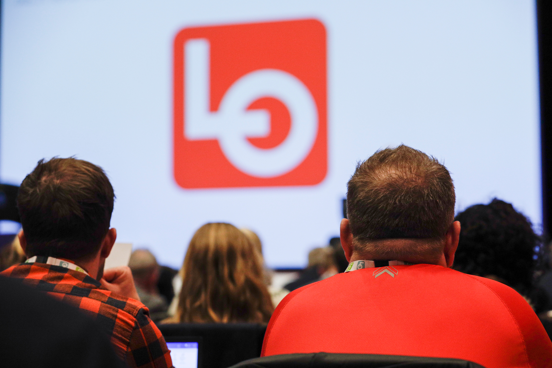 Folk i sal ser mot en skjerm med LO-logo. Foto.