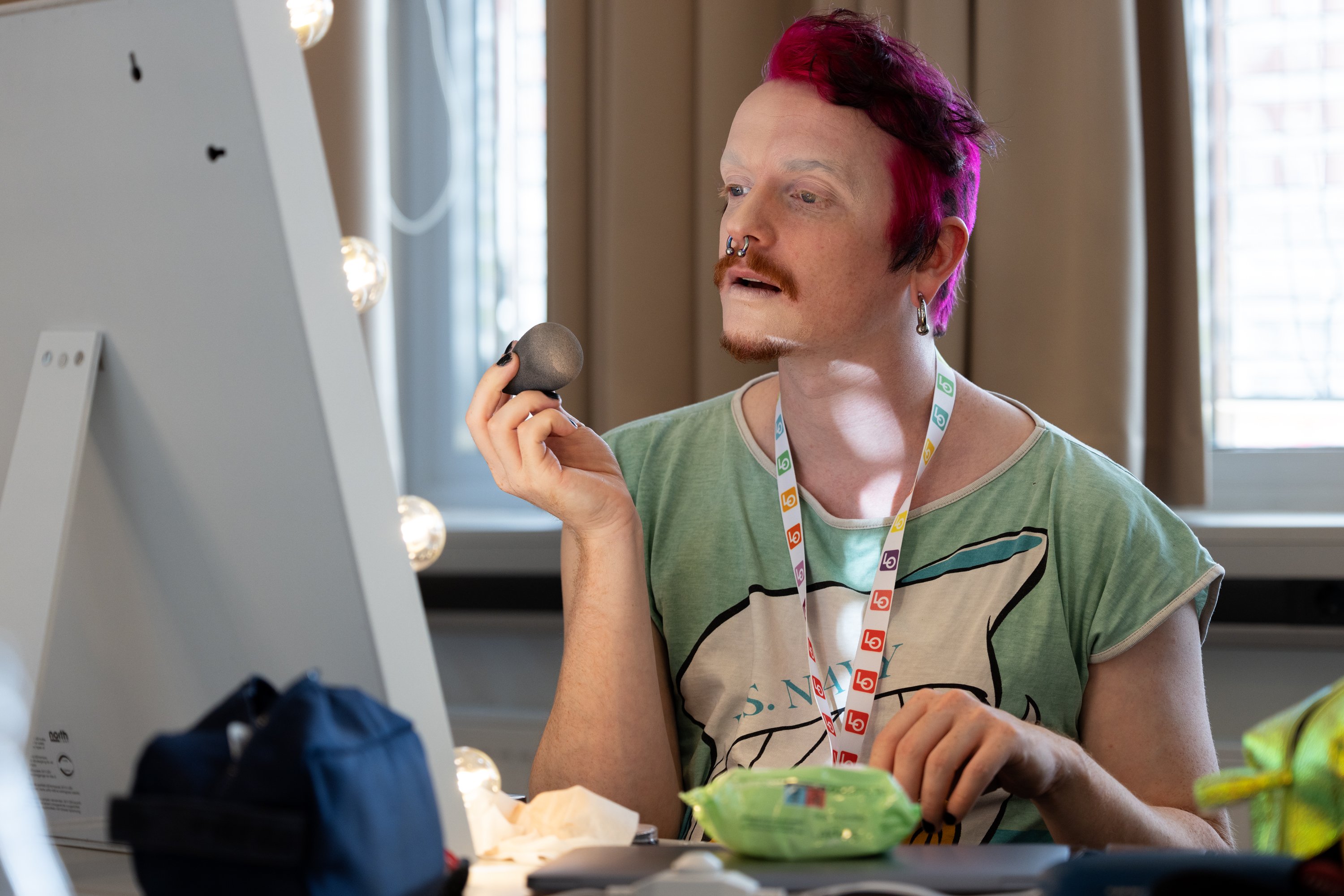 Dragartist sminker seg foran speil. Foto.