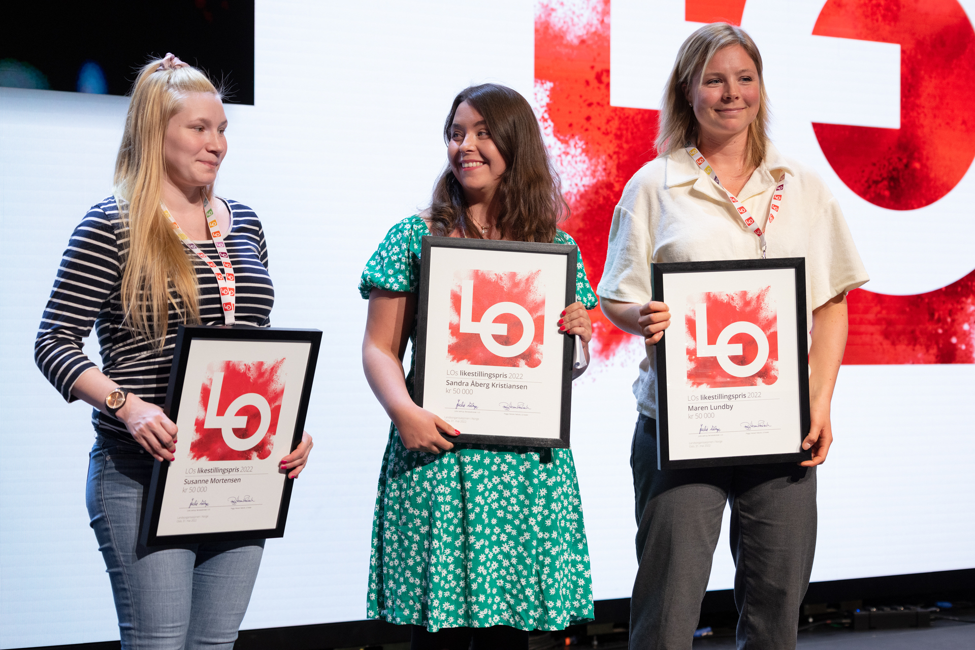 Tre unge kvinner står på scenen og mottar LOs likestillingspris. Foto