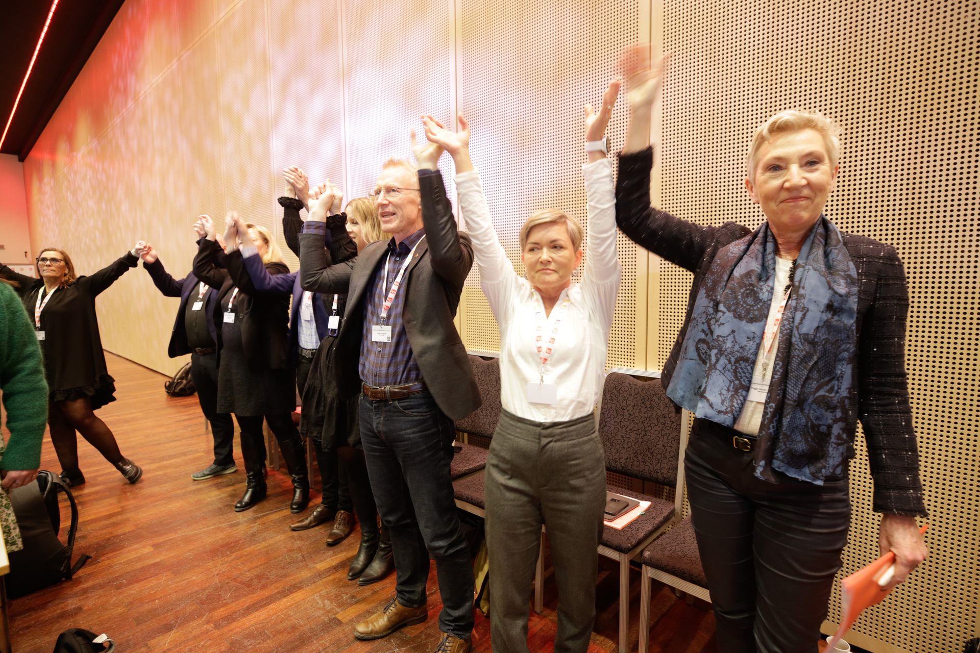 LOs politiske ledelse holder hender og synger allsang i sal. Foto