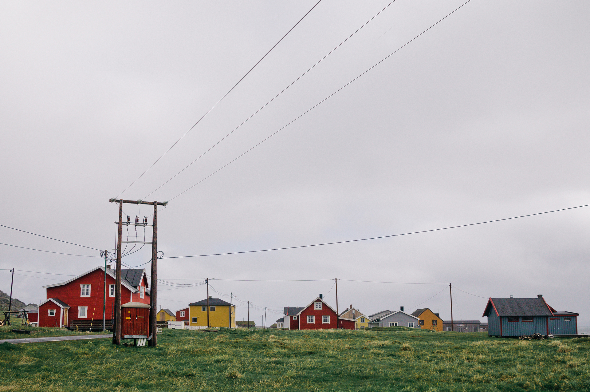 Strømmast foran en rekke med eneboliger. Foto.