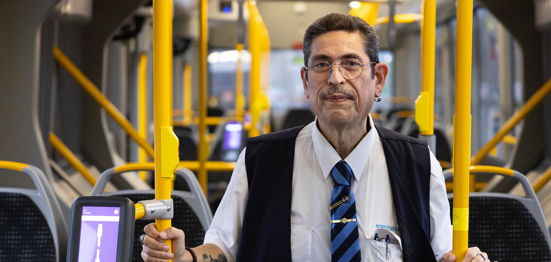 MAnnlig bussjåfør står inne i en buss. Foto