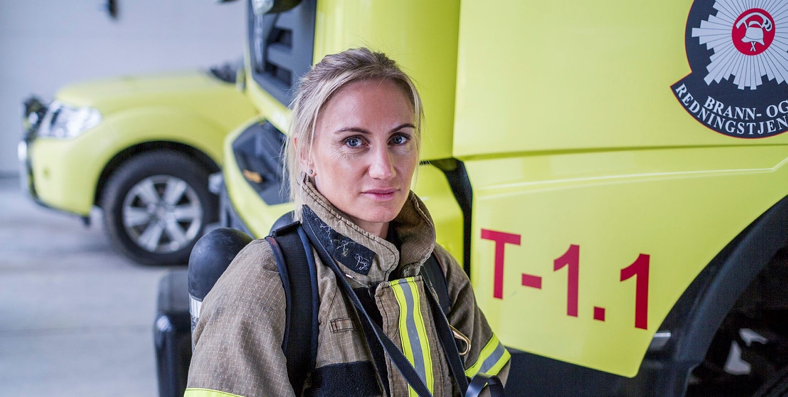 En kvinnelig brannkonstabel foran en brannbil