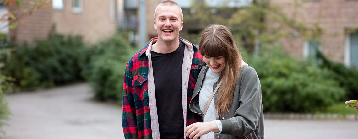 Ung mann og kvinne går sammen og holder rundt hverandre. Foto.