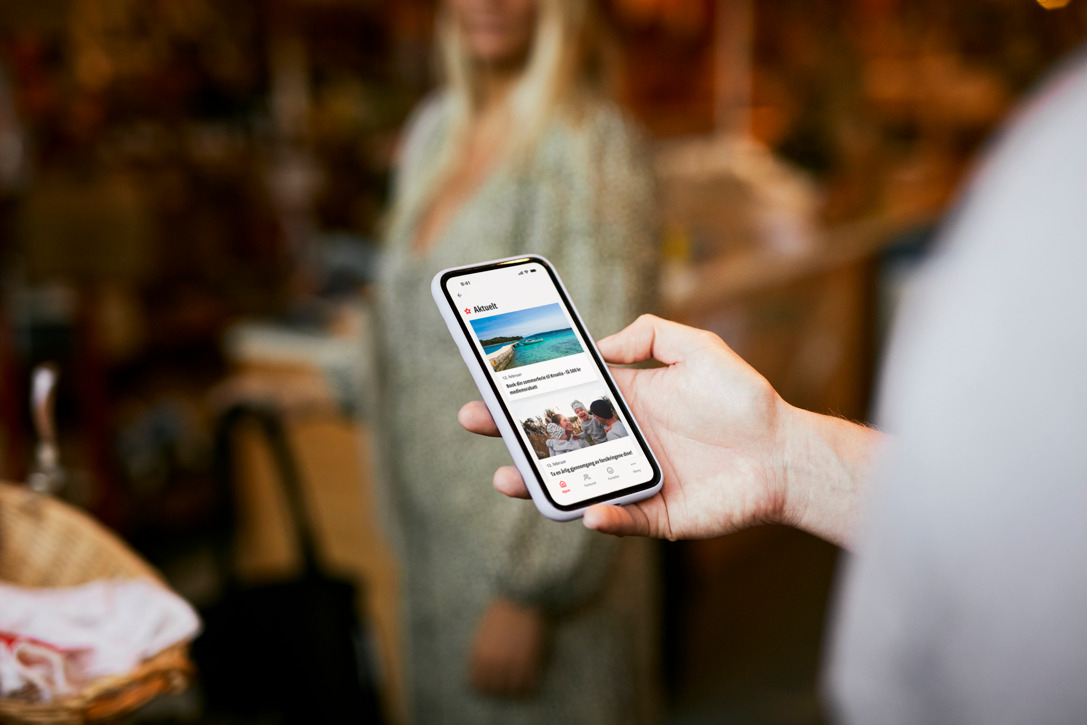 Utsnitt av person som holder en smarttelefon med LOfavør-appen oppe. Foto.