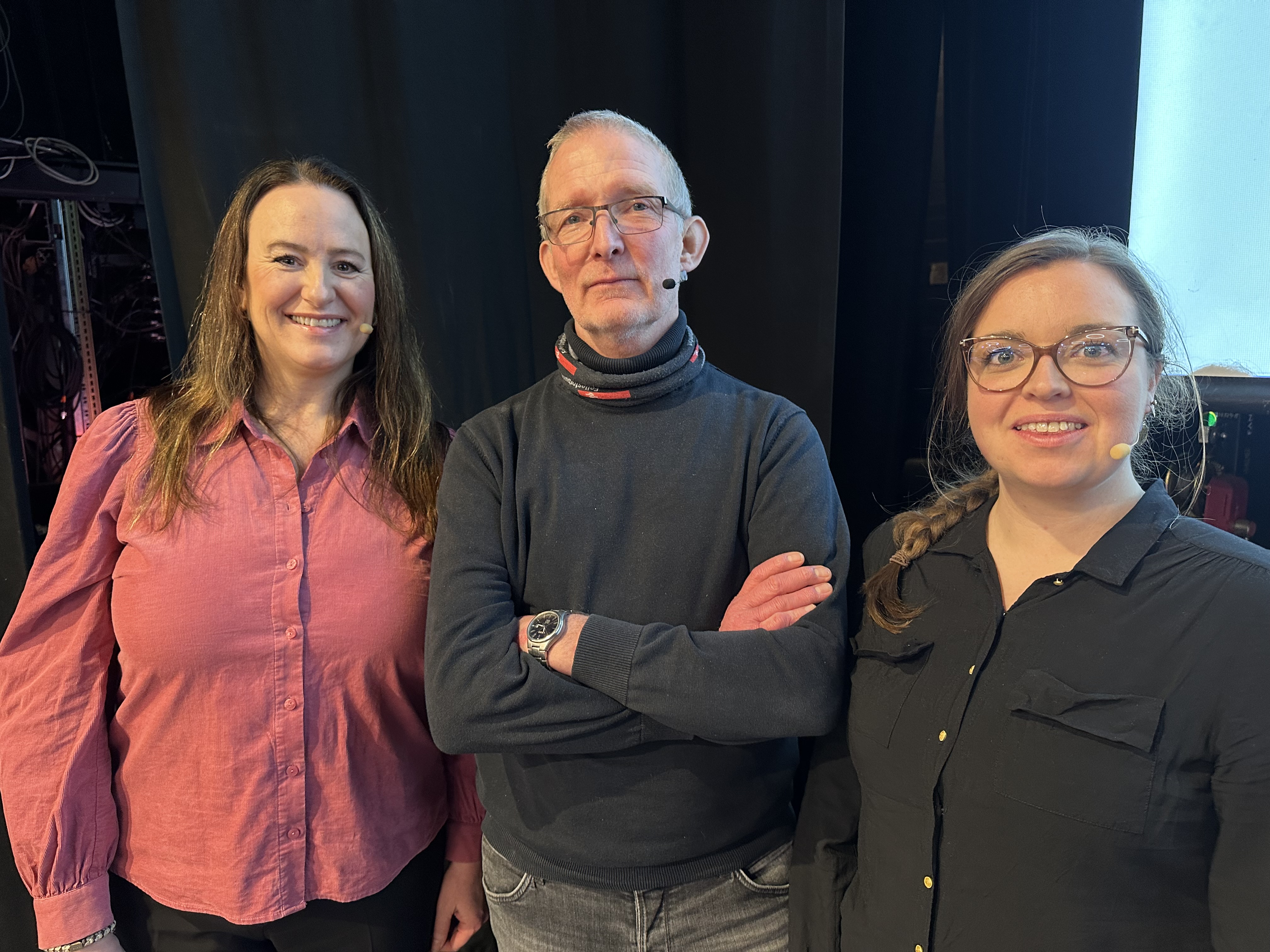 Tre LO-medlemmer står sammen side om side foran en scene. Foto.