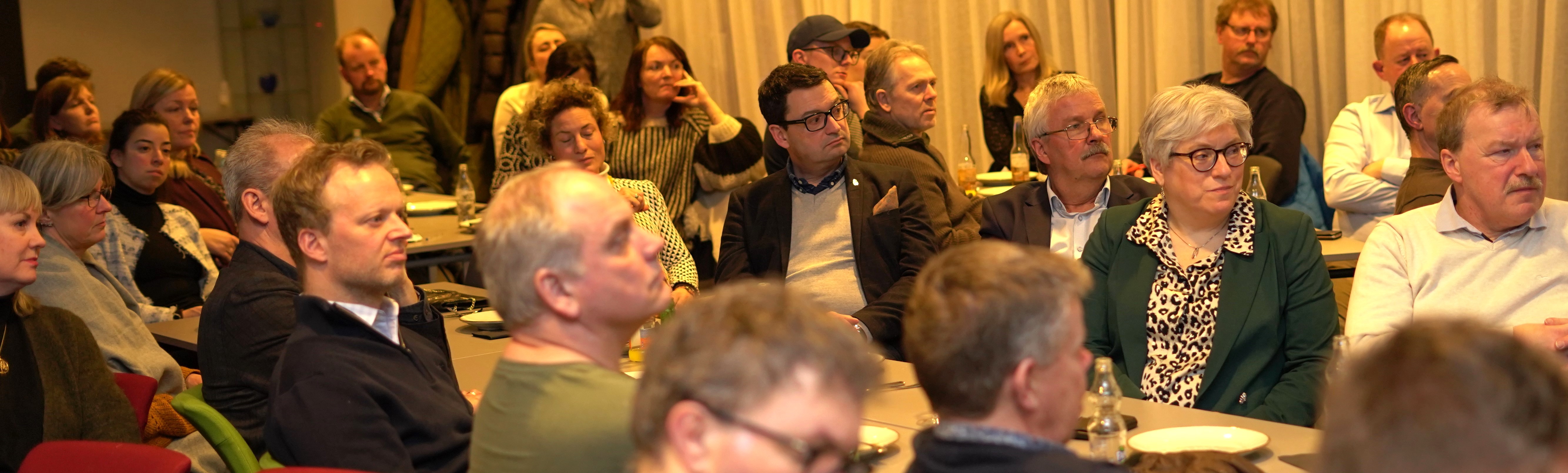 Møtedeltakere rundt bord med litt snacks og drikke