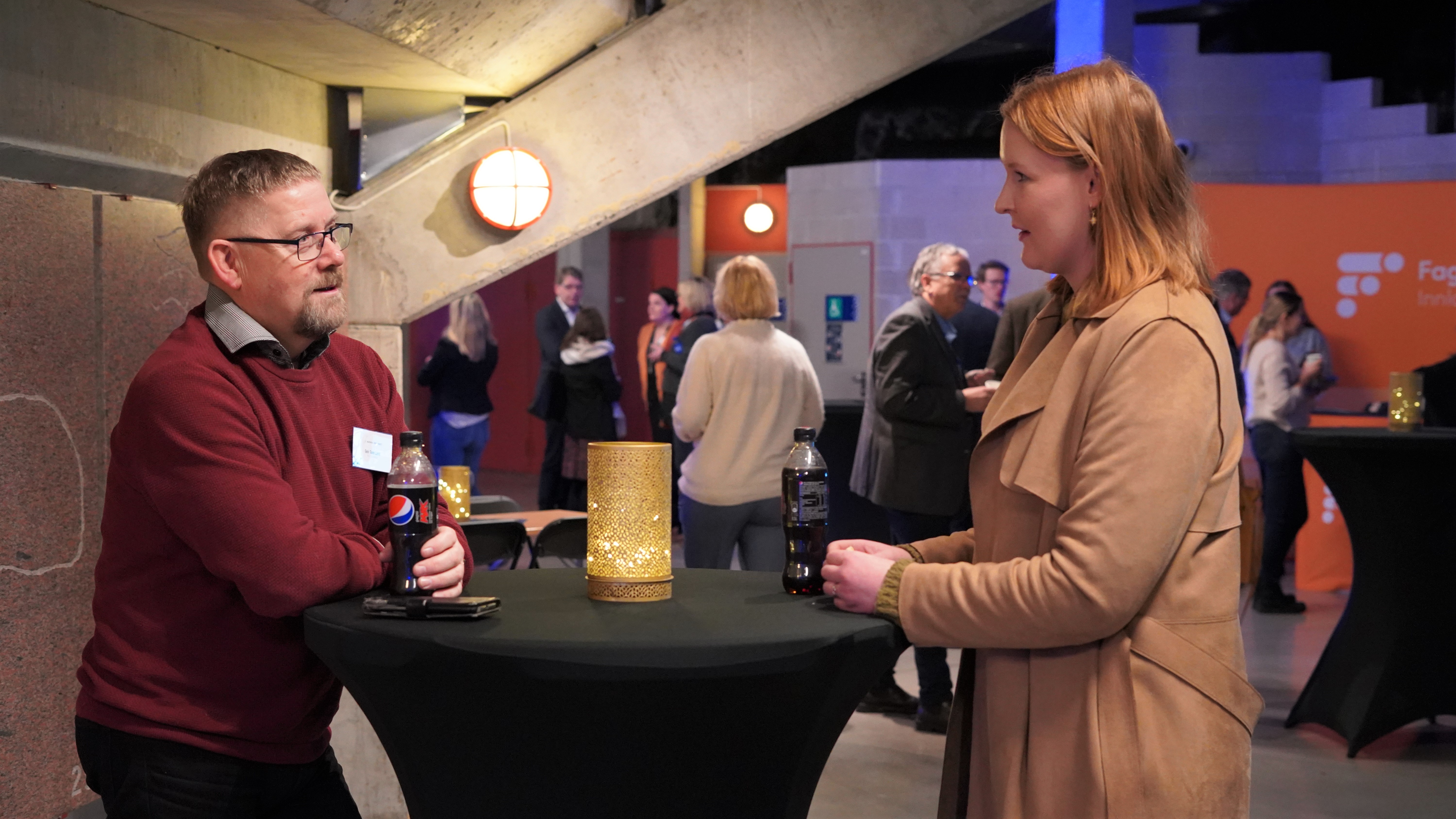 Mann 50+ og kvinne 30+ tar en prat over bordet i en møtepause