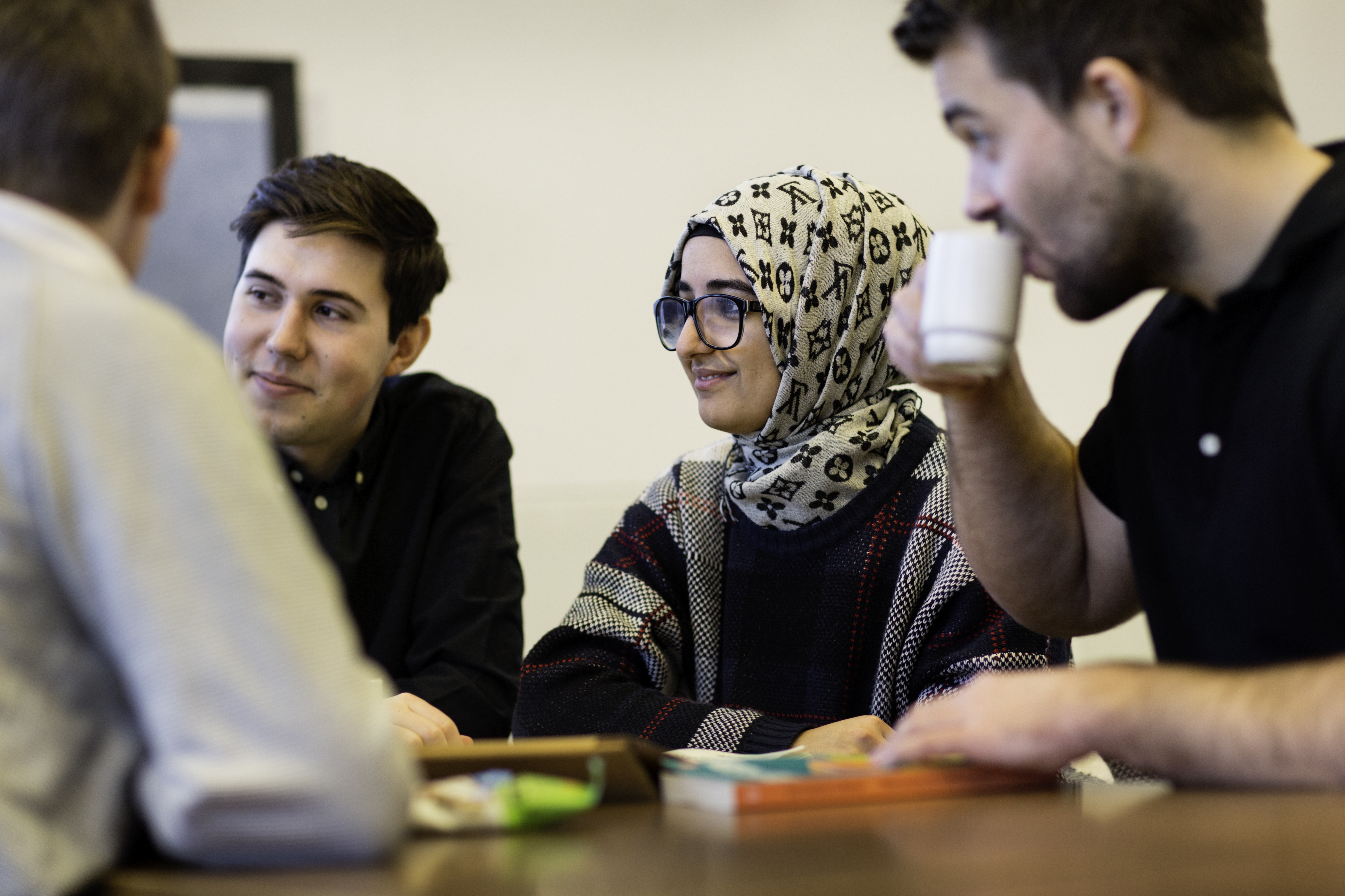 Fire studenter i ivrig samtale over en oppgave