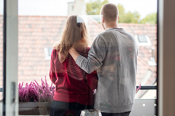 En kvinne og en mann holder om hverandre i sorg. Vi ser ryggen deres.