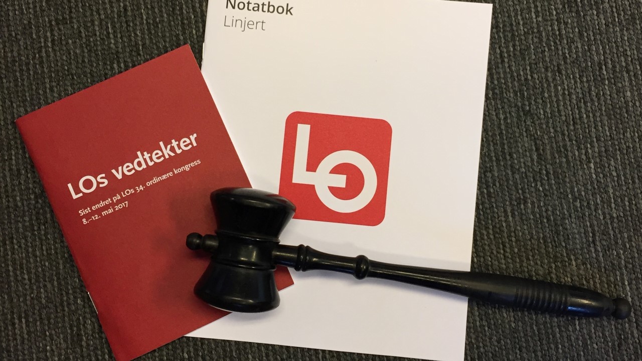 Bilde av en notatblokk, LOs vedteker og en klubbe. Illustrerer årsmøtedokumenter.