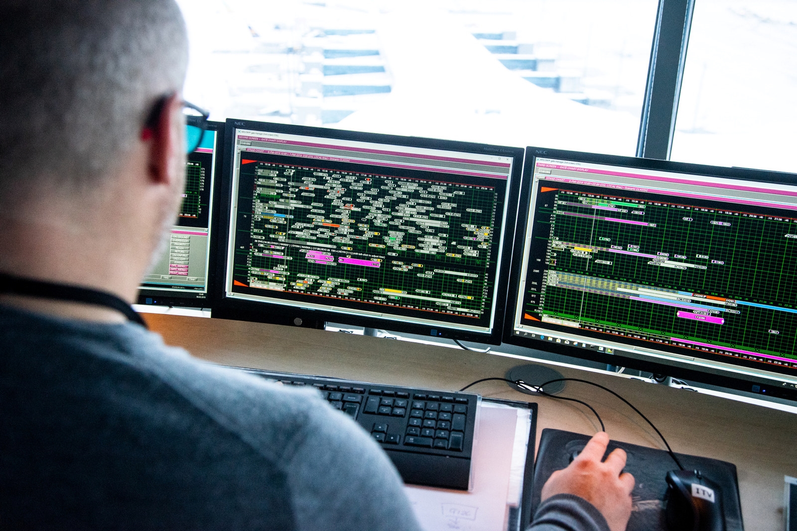 Bilde av en ansatt i flytårnet som overvåker flytrafikken via PC-skjermer.