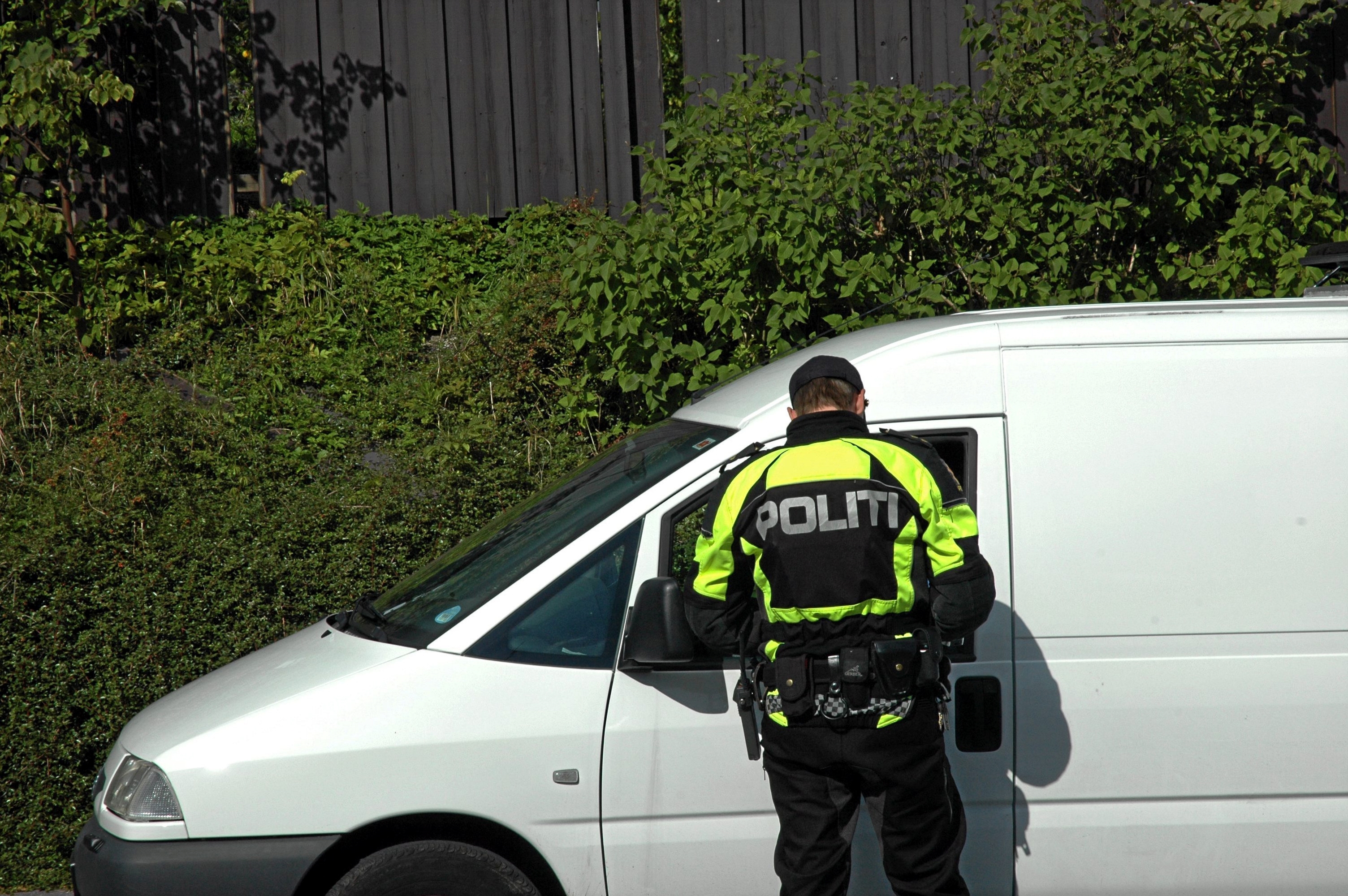 Politimann står ved hvit varebil