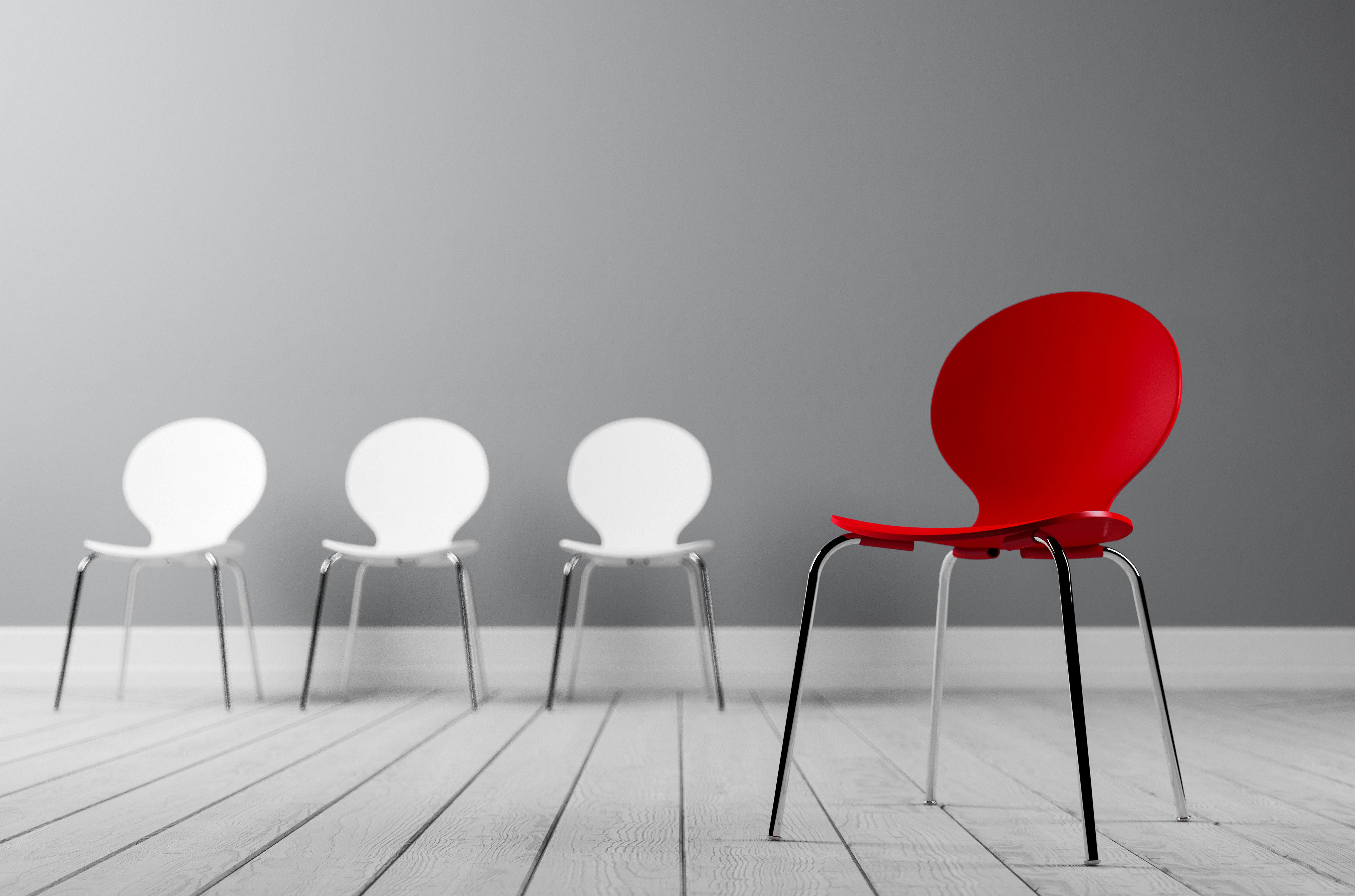 Tre hvite stoler og en rød stol som står litt lengre unna