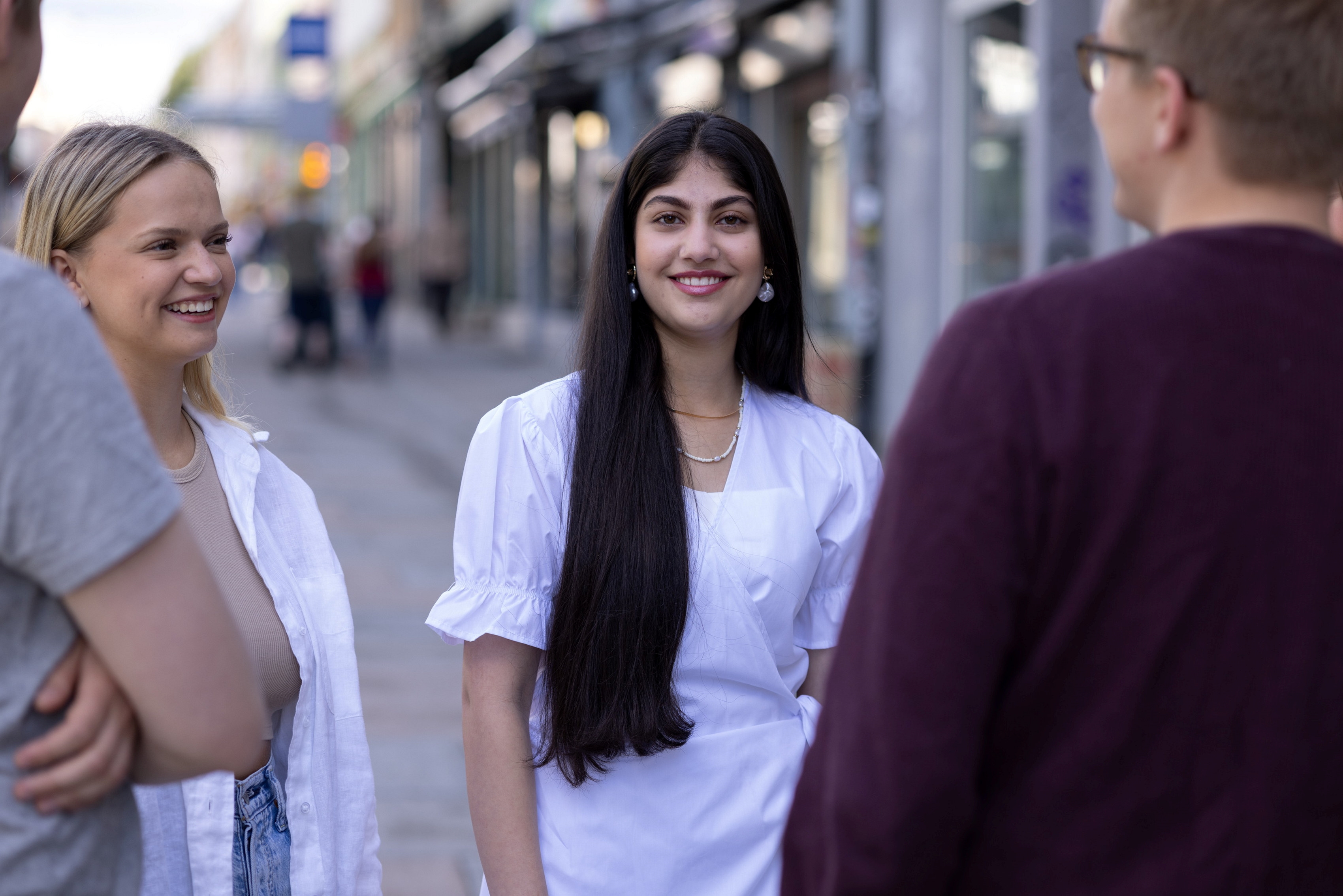 Unge folk står sammen og smiler utendørs. Foto.
