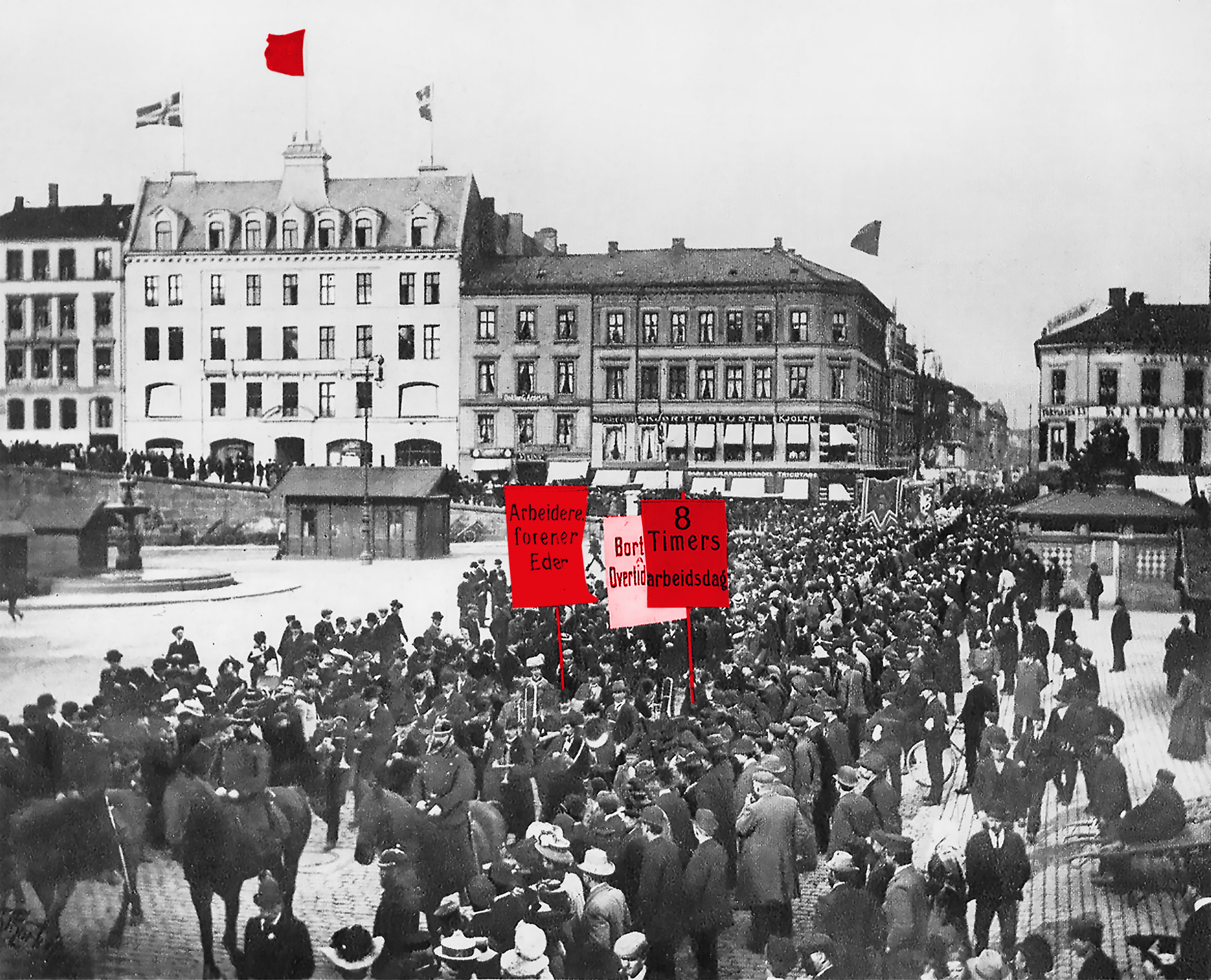 Bildet viser en 1. mai demonstrasjon i 1908 på Youngstorget i Kristiania (dagens Oslo). Fremst i toget rir politiet på hester, dernest et korps, etterfulgt av en folkemengde.